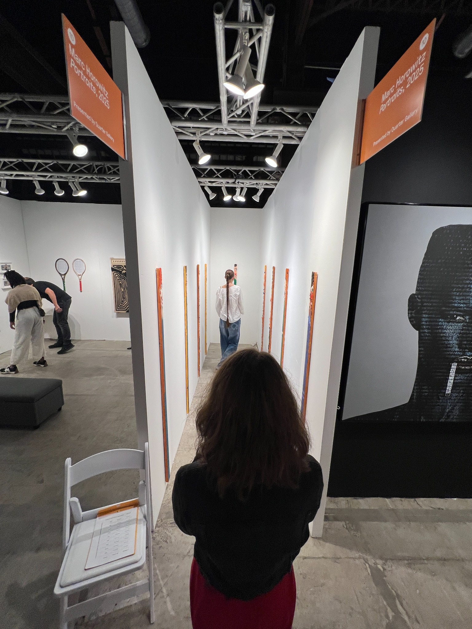 The narrow Quarter Gallery booth among neighboring art-fair booths, with visitors and orange exhibition signs.