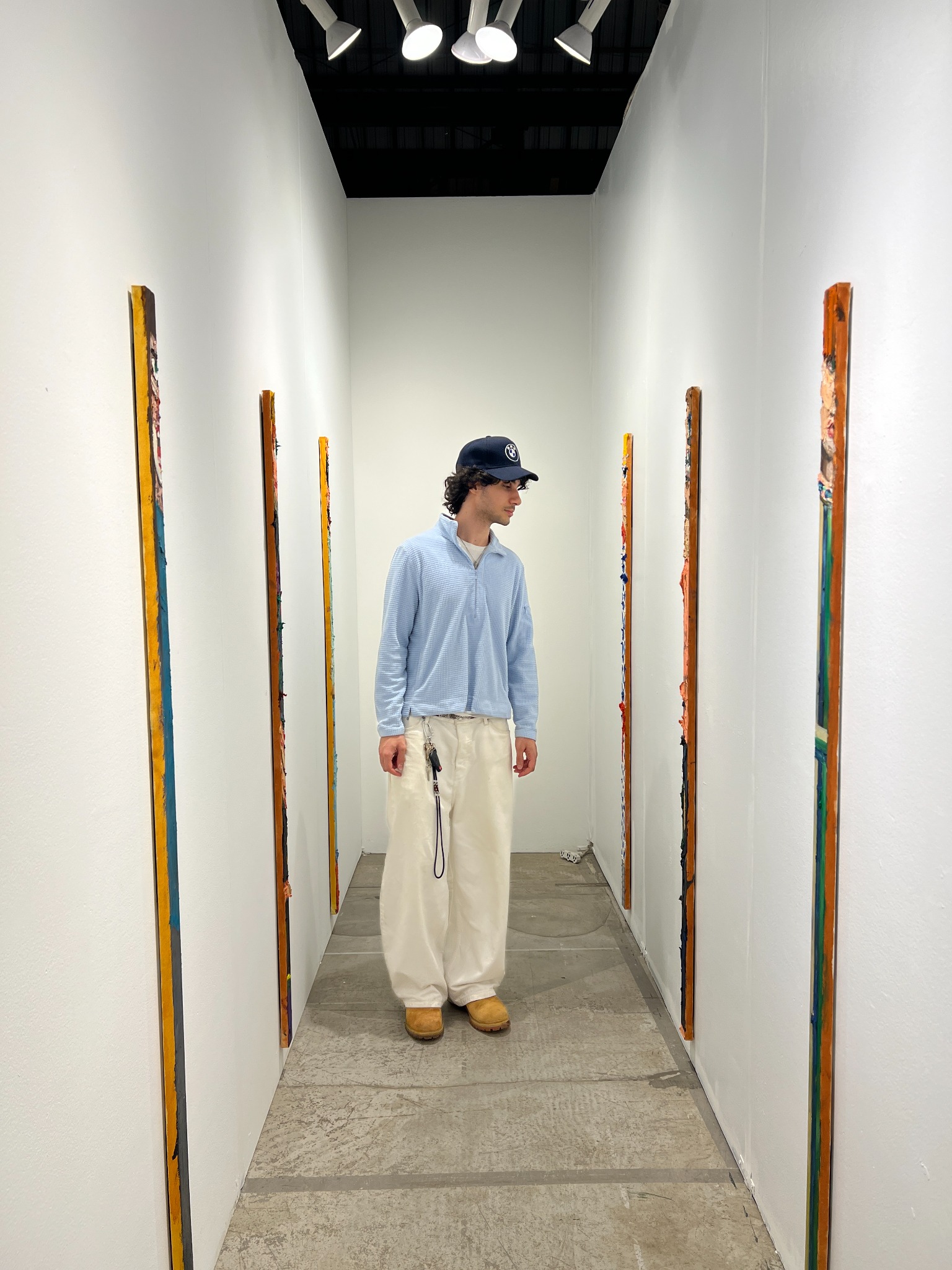 A visitor stands between the two walls of tall, two-inch-wide portraits.