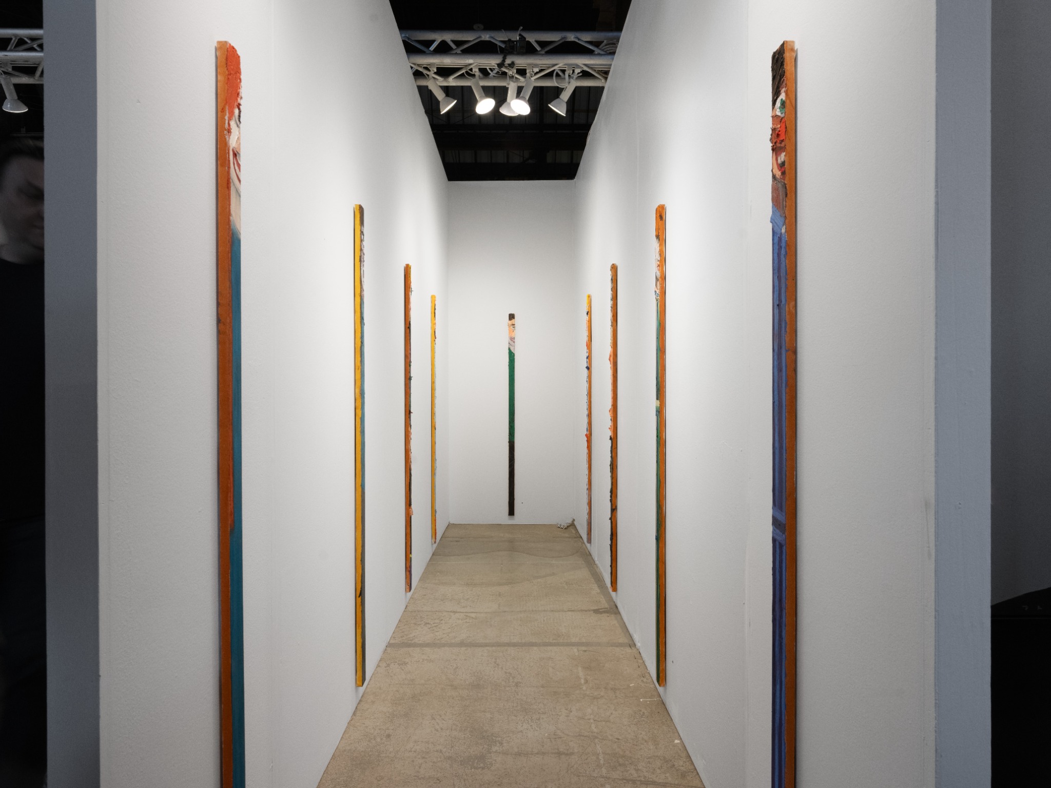 Tall, narrow portraits line both sides of a four-foot-wide gallery booth.